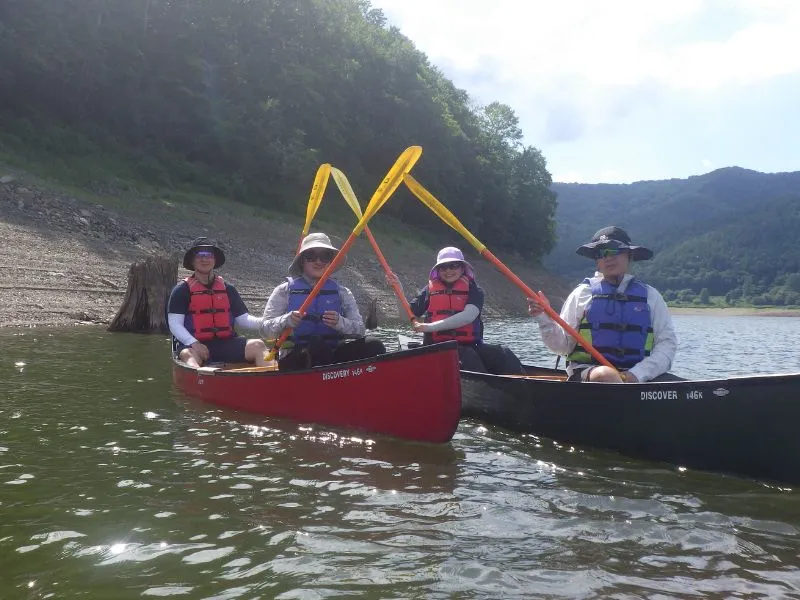 A group of four friends in two canoes having fun together, crossing their paddles in a playful pose.