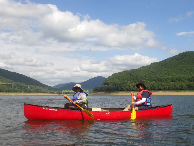 Two people enjoying a relaxing and peaceful canoe tour on the calm waters of a lake.