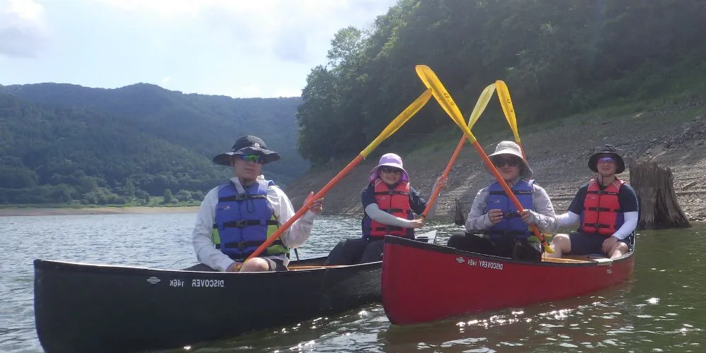 Two canoes with four participants launching onto the lake, ready for their adventure.