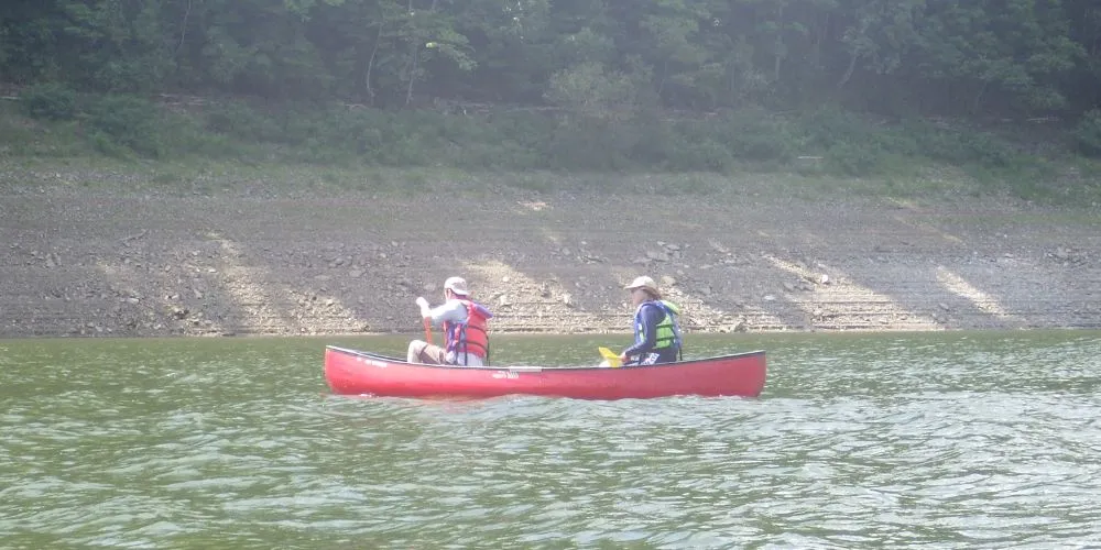 A couple paddling a red canoe, enjoying a quiet and peaceful moment on the water.