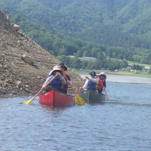 Two canoes exploring a narrow cove along the steep, rocky shoreline of the lake.