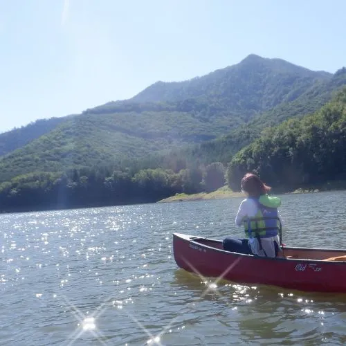 A couple enjoying a canoe ride on a sunny day, with the water sparkling around them.