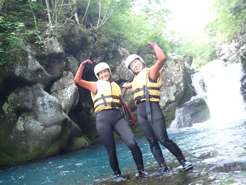 Two participants flexing their muscles and smiling, feeling empowered after conquering a section of the Wild Canyoning tour.