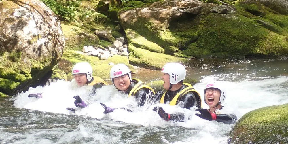 A group of friends laughing and enjoying the powerful whitewater in a natural jacuzzi during the Wild Canyoning tour.