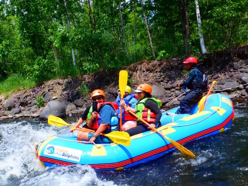 A rafter capturing the exciting moments on their phone while navigating the lush, green banks of the Chubetsu River.