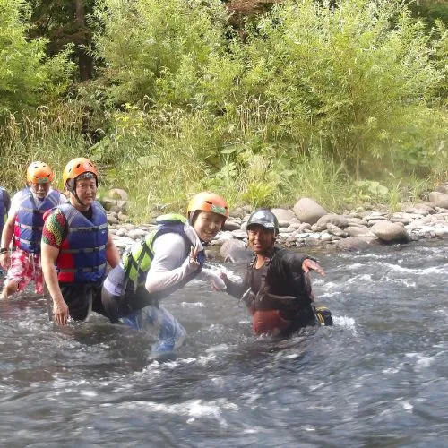 Participants laughing and playing in the shallow water, being helped by a guide in a fun moment.