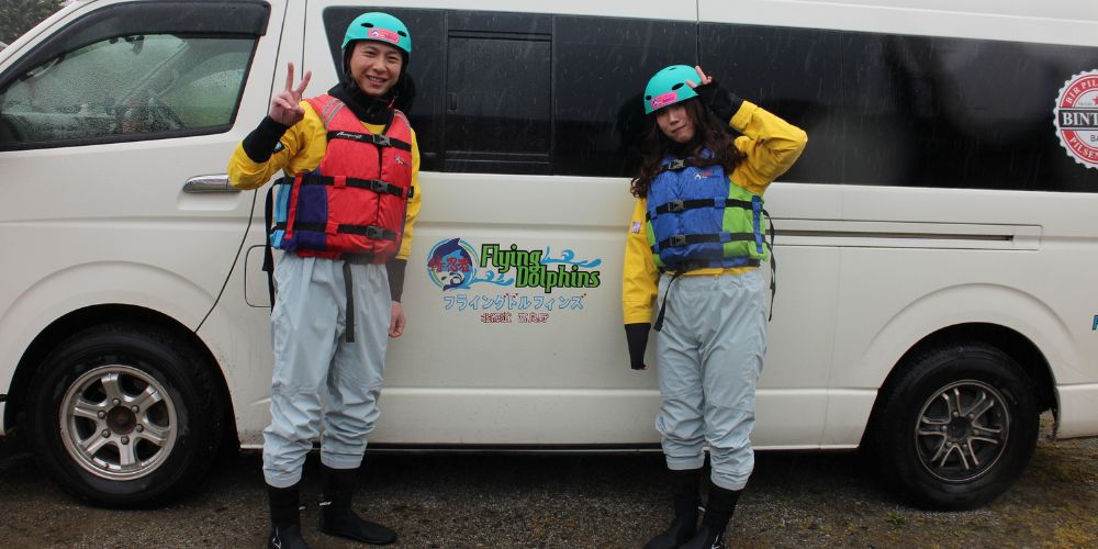 Two participants posing happily in front of the tour van, fully geared up for their ducky adventure.