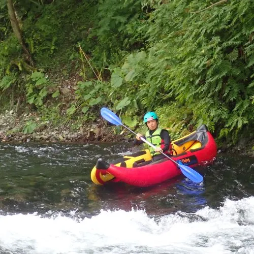 A person in a ducky navigating a small rapid, with water splashing around.