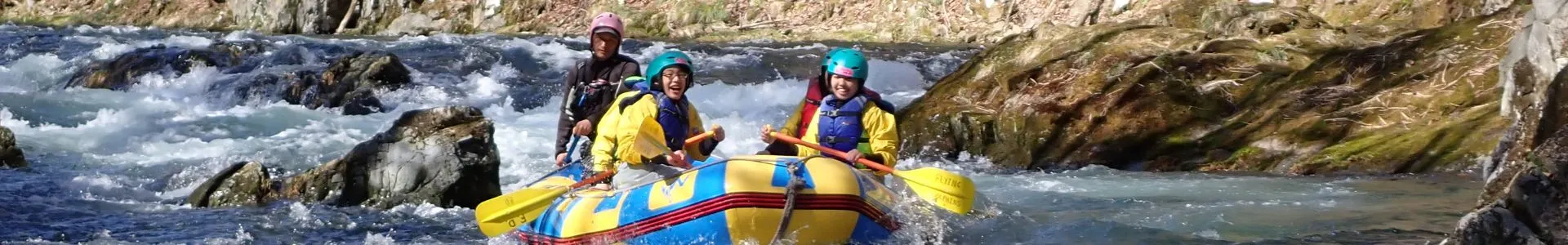 A group of people cheerfully rafting down a river in Furano.