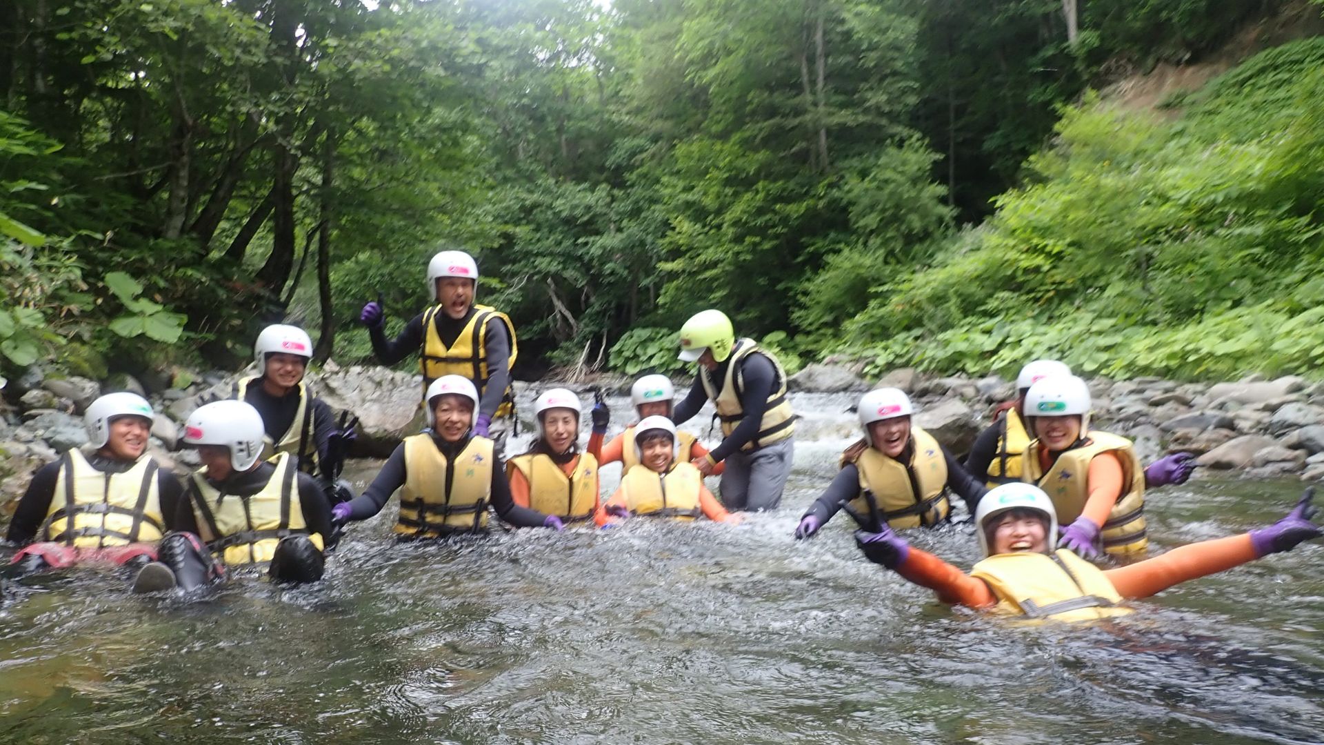 A group of adventurers laughing together in a crystal clear canyon pool.