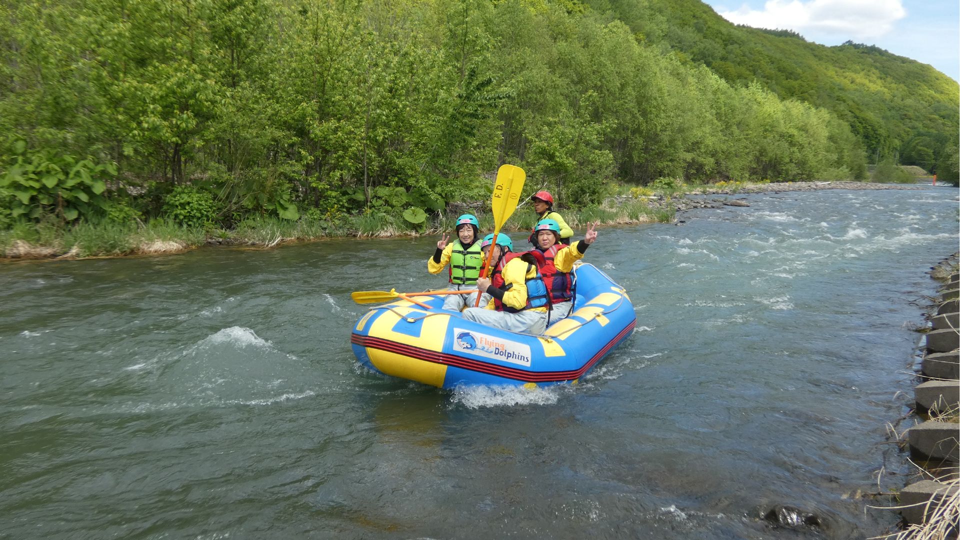 A team of rafters celebrating with raised paddles as they successfully navigate through exciting whitewater rapids on a sunny day.
