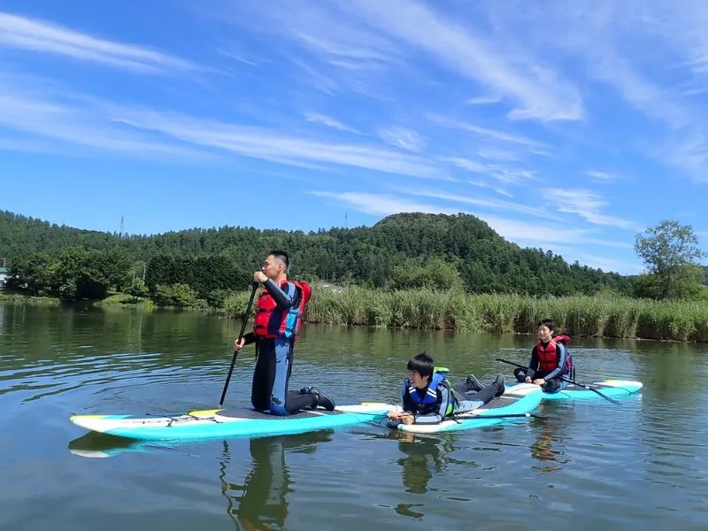 Three participants enjoying a peaceful SUP tour on a calm lake, showcasing the relaxing and versatile nature of the activity.