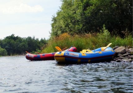 A group of people rafting on a vibrant blue river surrounded by lush green mountains
