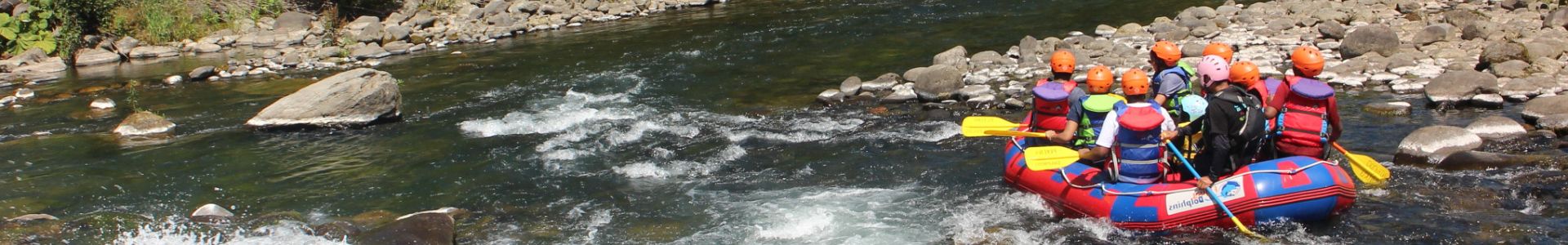 A group of people rafting on a vibrant blue river surrounded by lush green mountains