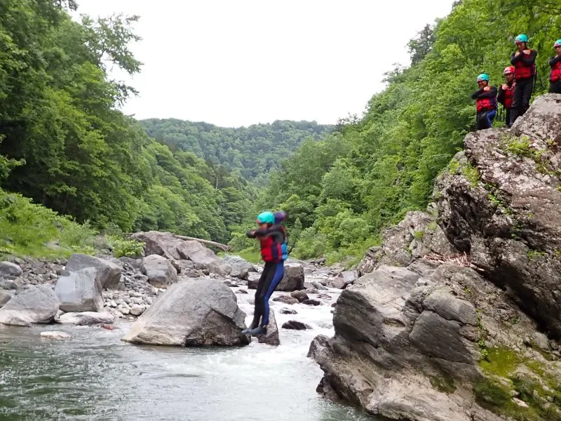 An adventurous participant mid-air, having taken a bold jump from a high cliff into the river, a dynamic part of the tour.