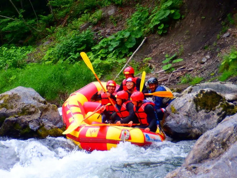 A team of rafters navigating through a narrow, challenging gorge on the Mukawa River, showcasing the thrilling nature of the course.