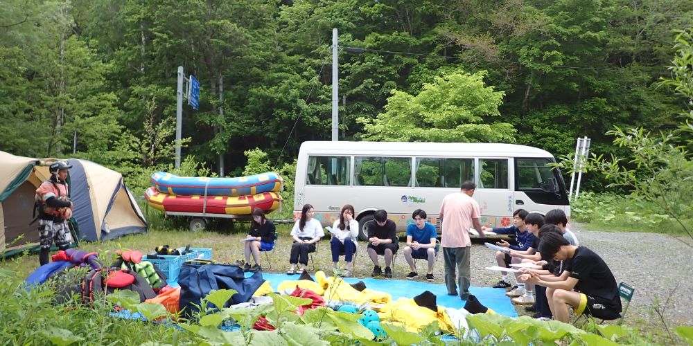 Participants listening to a guide during the check-in and orientation process at the Mukawa River base camp.