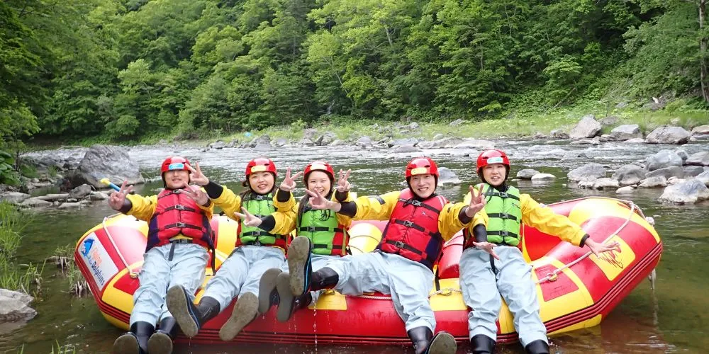 A happy group of rafters making peace signs and relaxing on the boat after successfully navigating a challenging section.