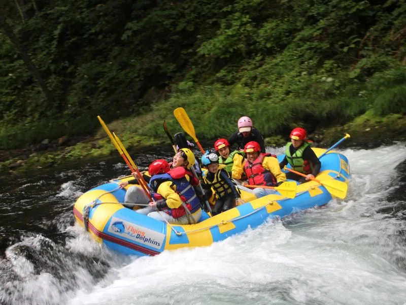 A rafting boat floating on the crystal clear Sorachi River, with the riverbed visible.