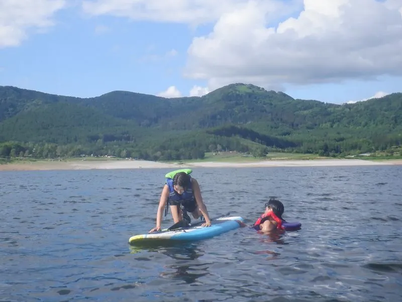 A participant laughing while getting back on their SUP board from the water, showing it's safe and fun to fall in.