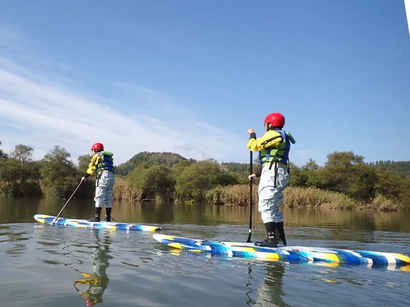 Two smiling participants standing confidently on their paddleboards, showcasing how easy it is for beginners to enjoy.