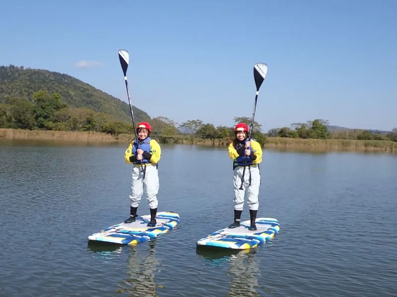 Two people paddling their SUPs across the calm, mirror-like surface of Lake Nokanan on a sunny day.