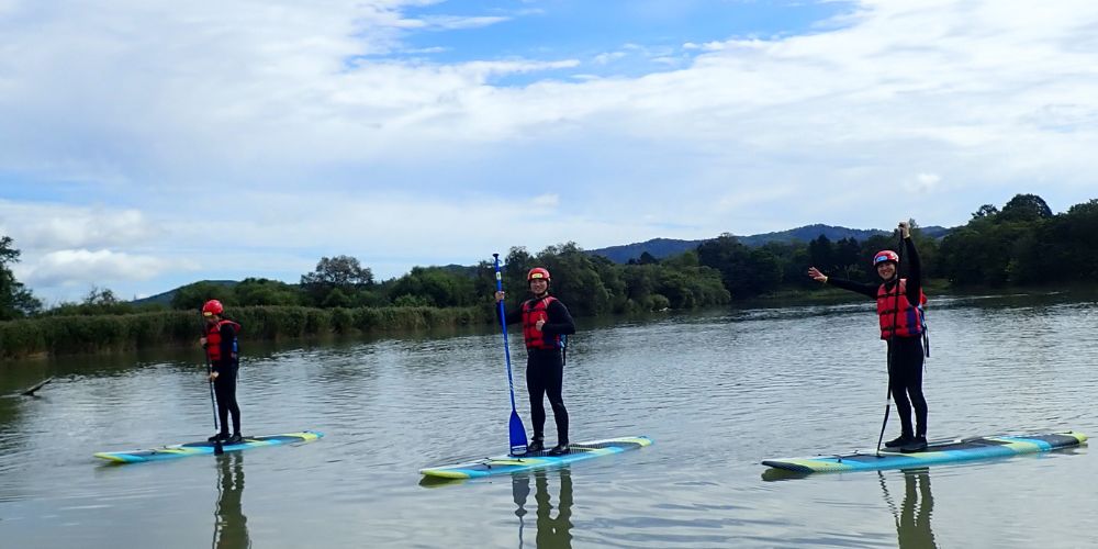 A participant smiling brightly while enjoying a relaxing paddle on their SUP board on a sunny day.