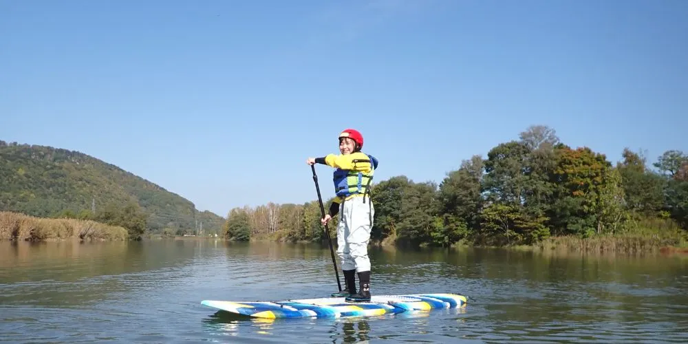 Two participants celebrating with excitement in front of the tour van after their SUP adventure.