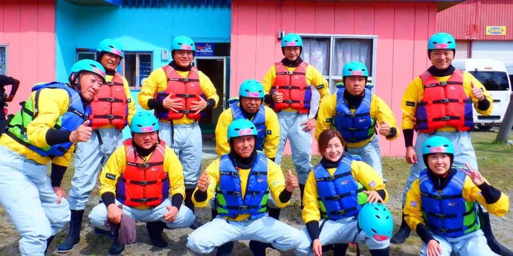 A large group of happy participants giving a thumbs-up in front of the base building after the tour.