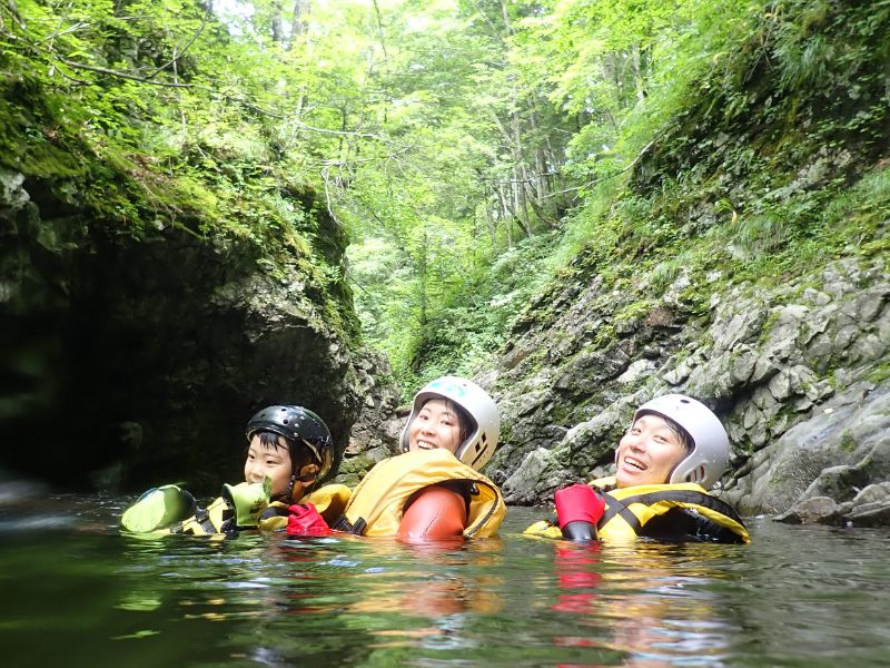 A group of adventurers exploring a stunning gorge, navigating along the rock walls next to the clear river.