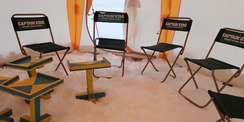 The interior of an ice fishing tent, showing the provided chairs and small fishing tables.