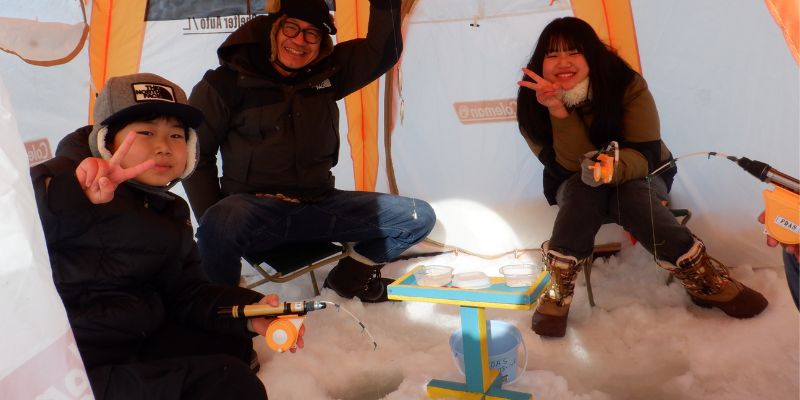 A guide drilling a hole in the thick ice with an ice auger.