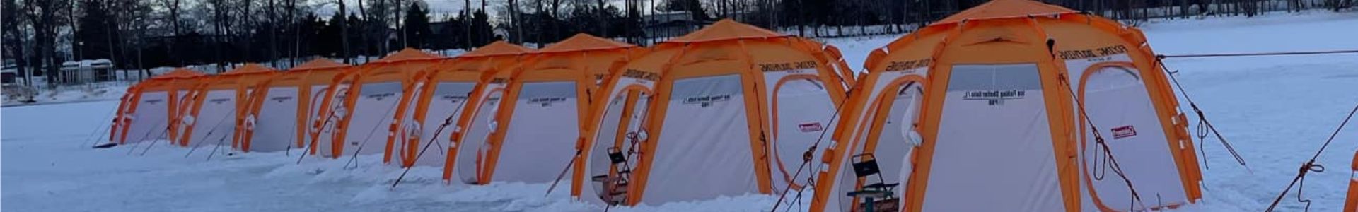 A family enjoying ice fishing from inside a warm tent on a frozen lake.