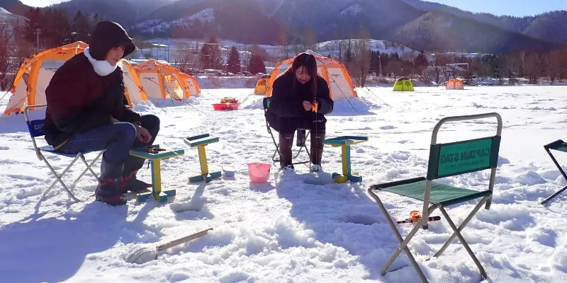 A car parked near a frozen lake in a winter landscape.