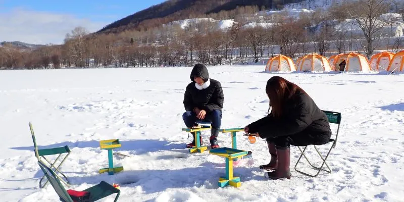 A family enjoying ice fishing in a tent.