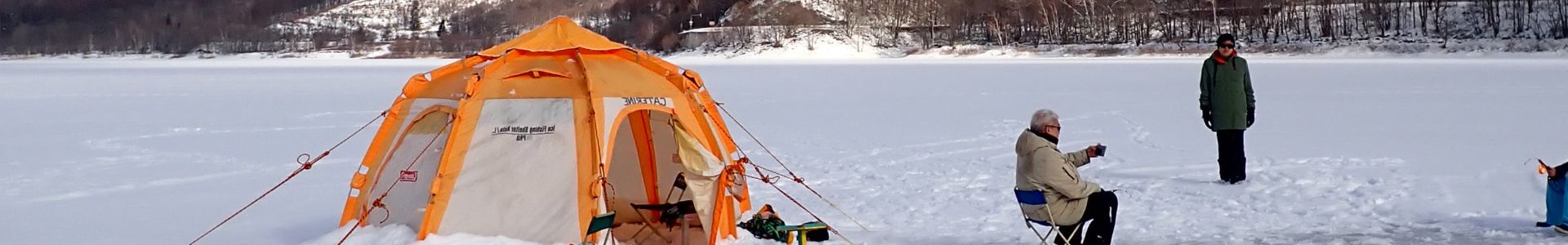 A beautiful snowy landscape in Furano with a skier and an ice fishing tent.
