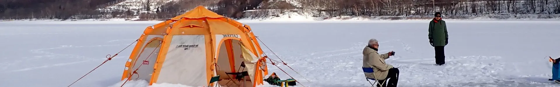 A beautiful snowy landscape in Furano with a skier and an ice fishing tent.