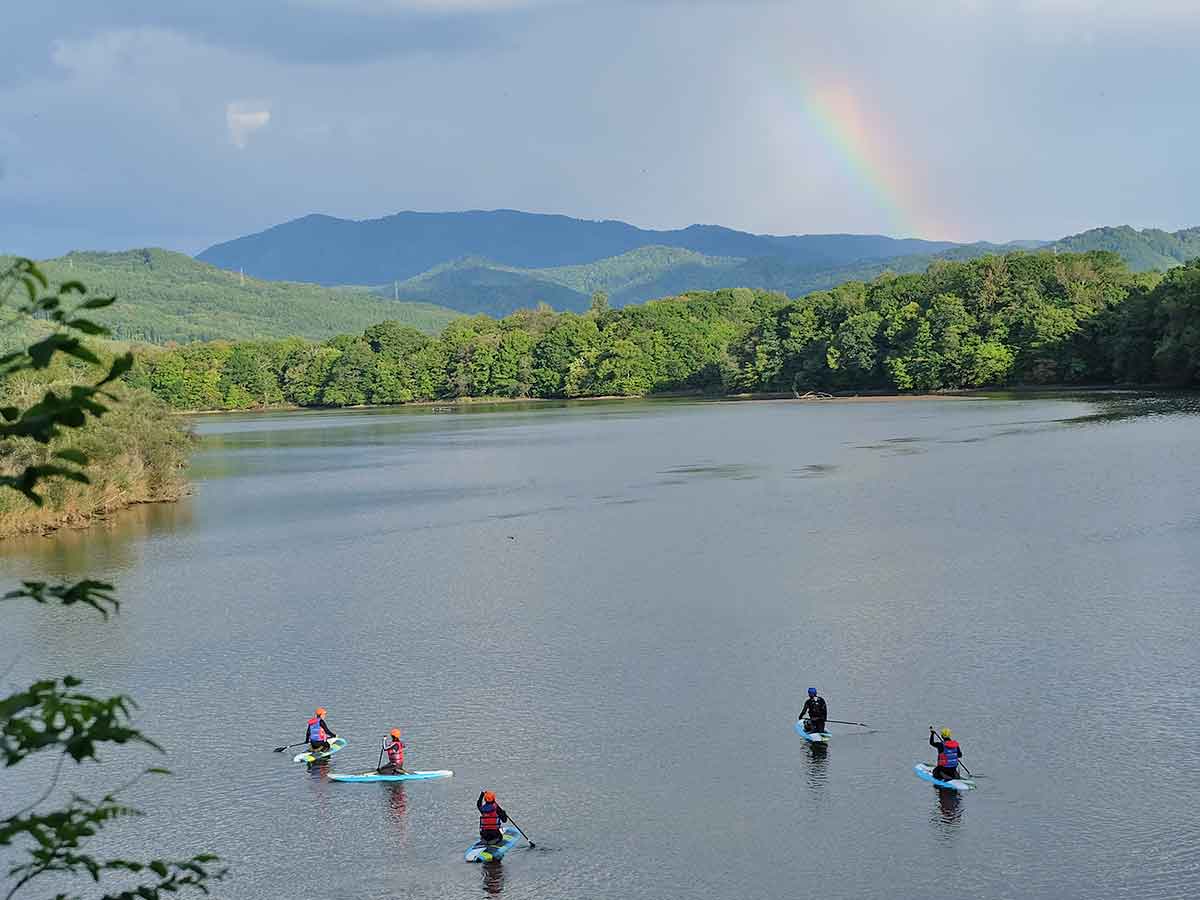 湖畔にかかる虹を見ながらSUPを楽しむ